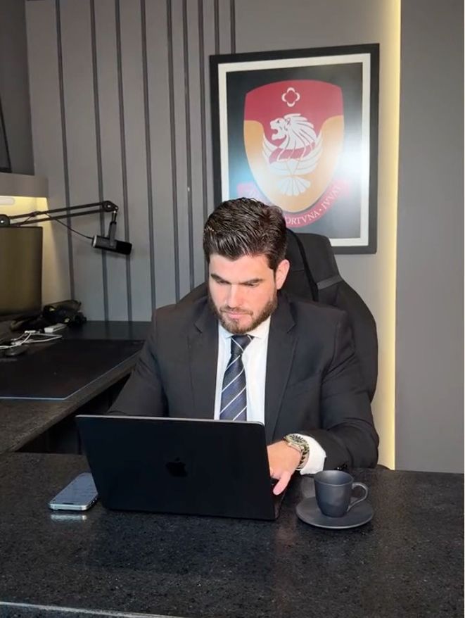 Israel Borges no escritório, com o brasão ao fundo